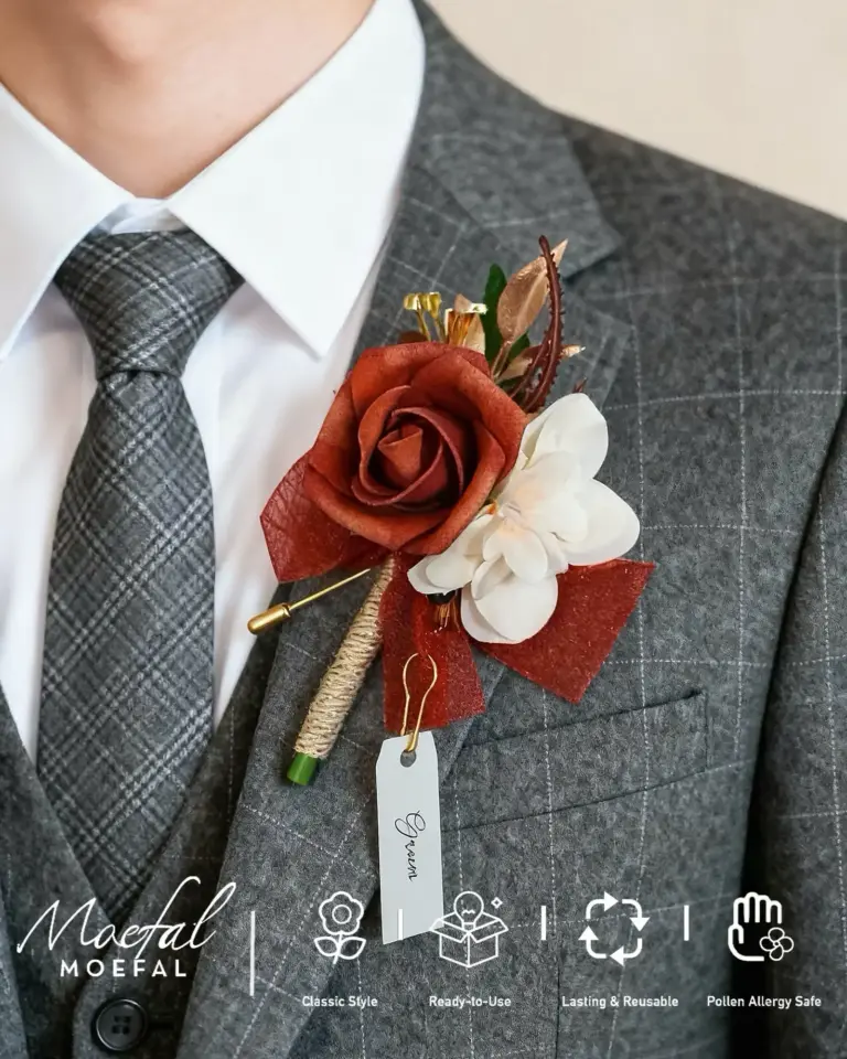 Close-up of a groom wearing a terracotta boutonniere on his gray plaid suit.