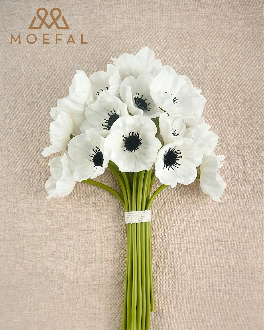 A finished hand-tied white anemone bouquet lying flat on a textured neutral background.