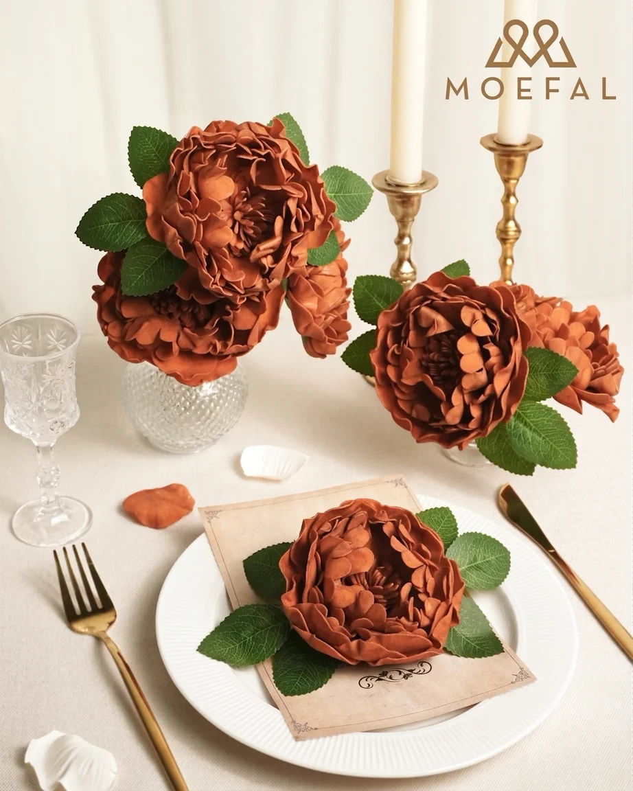 A romantic wedding table setting decorated with artificial terracotta peonies on a white plate.