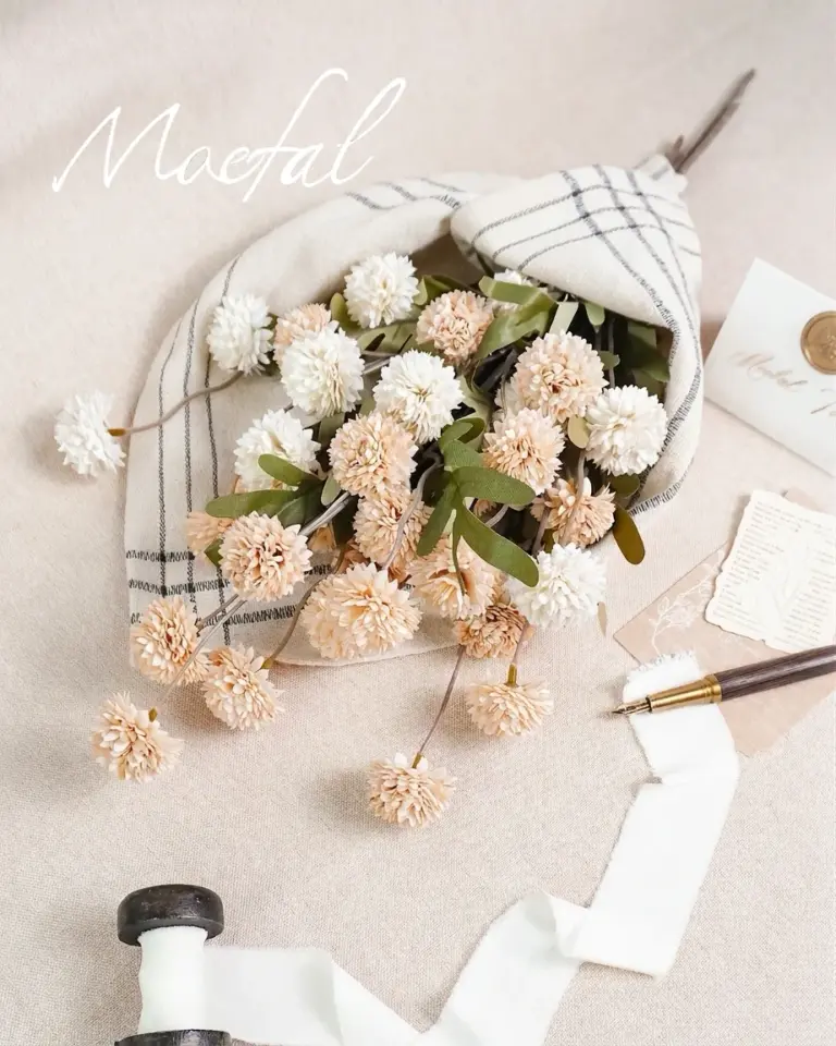 A bouquet of beige pompon mums styled with a ribbon and vintage letter.