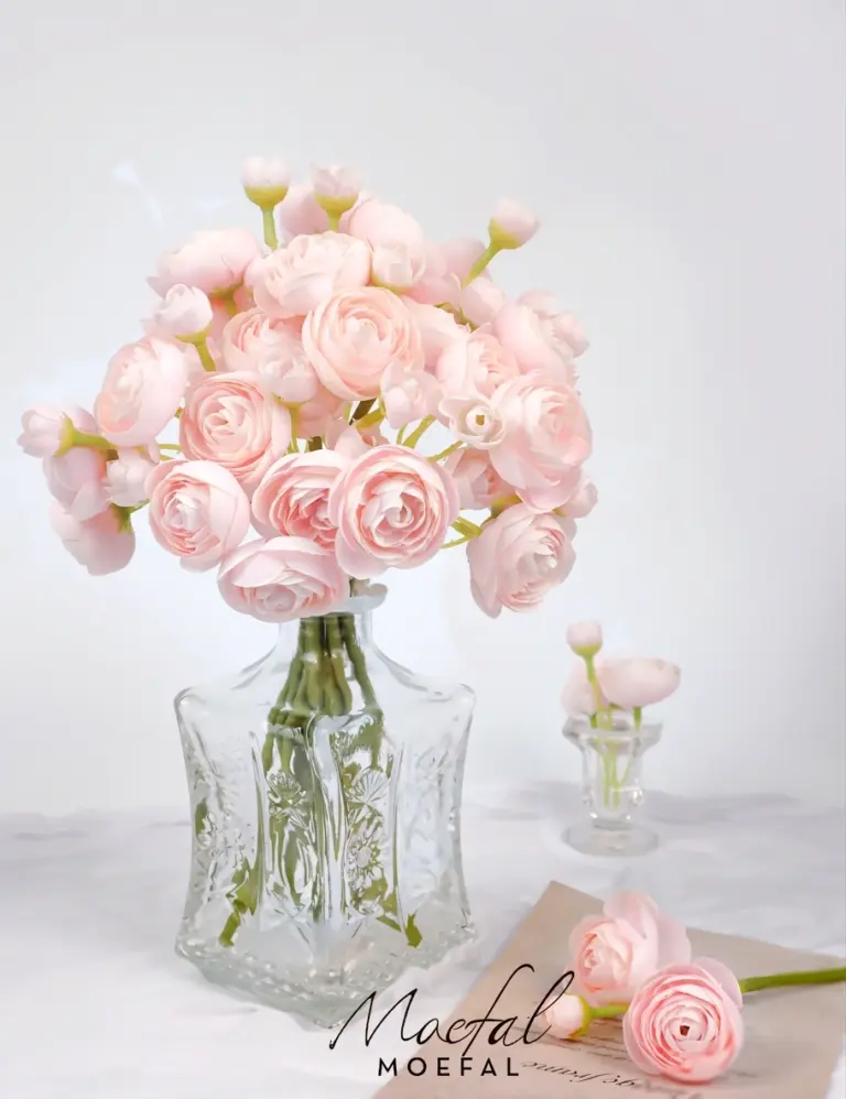 A bouquet of blush pink ranunculus arranged in an elegant vintage glass vase.