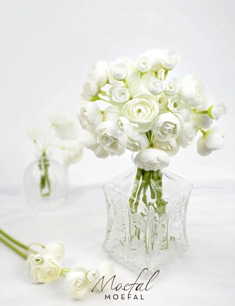 A beautiful bundle of white bud vase ranunculus in a vintage clear glass vase.