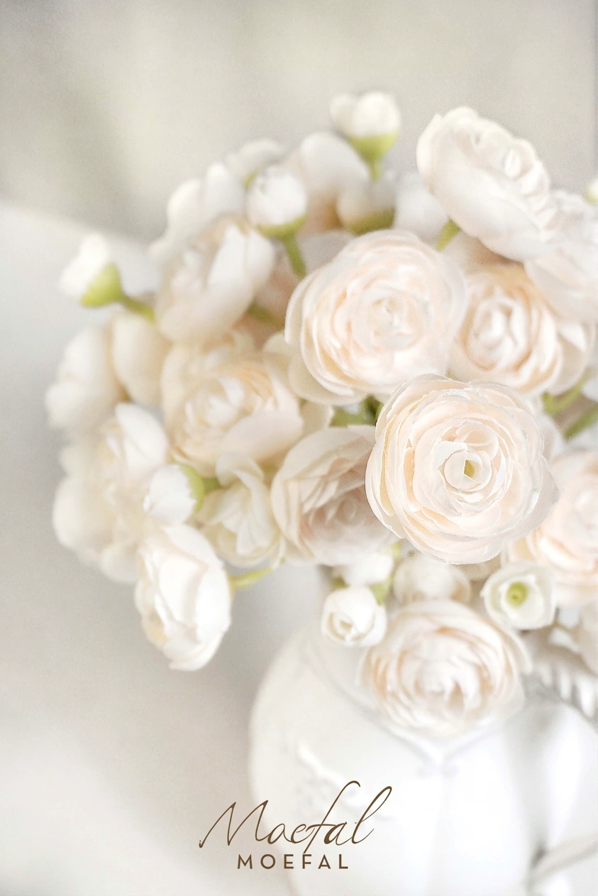 A soft-focus closeup on the delicate swirling petals of cream ranunculus flowers.