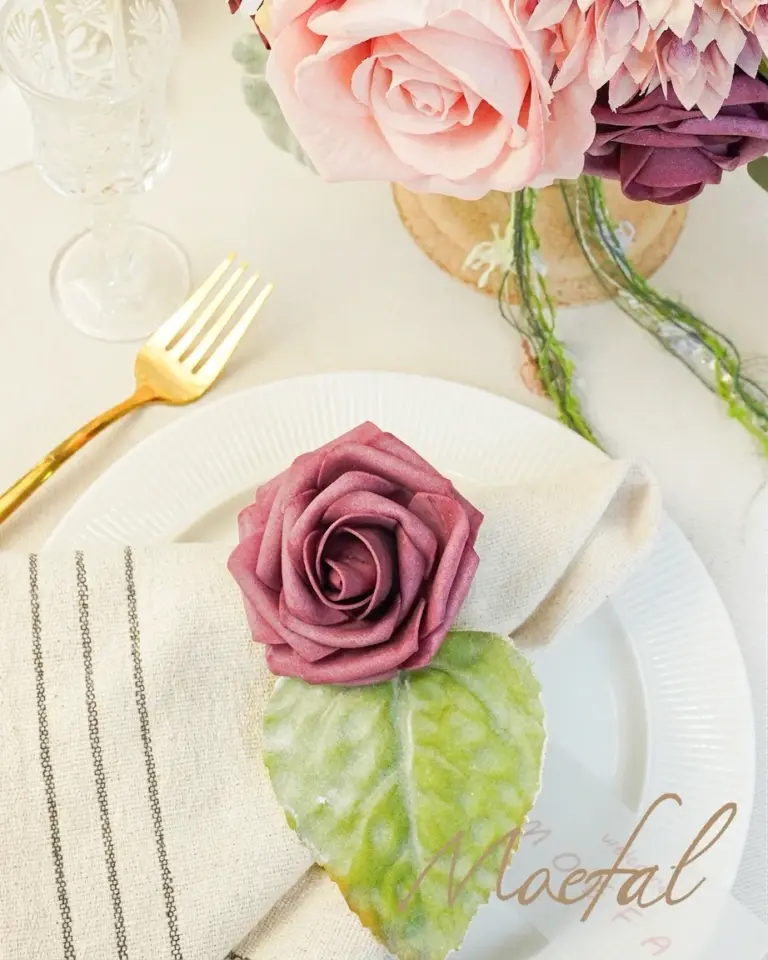 A single burgundy rose on a napkin for a DIY spring wedding flowers table setting.