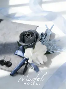 A stylish groom boutonniere with a silver rose and blue ribbon on a suit.