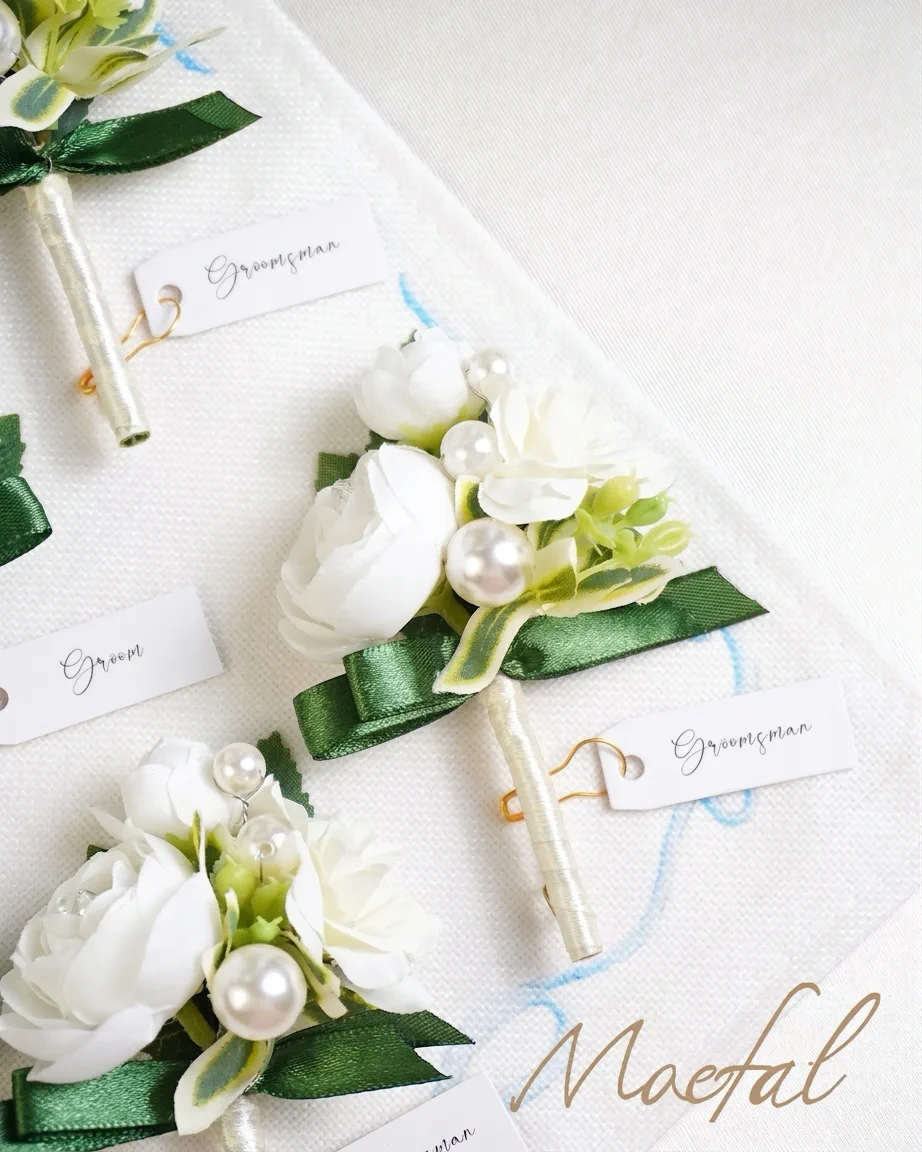 A detailed view of several pieces from the groomsmen boutonniere set on white fabric.