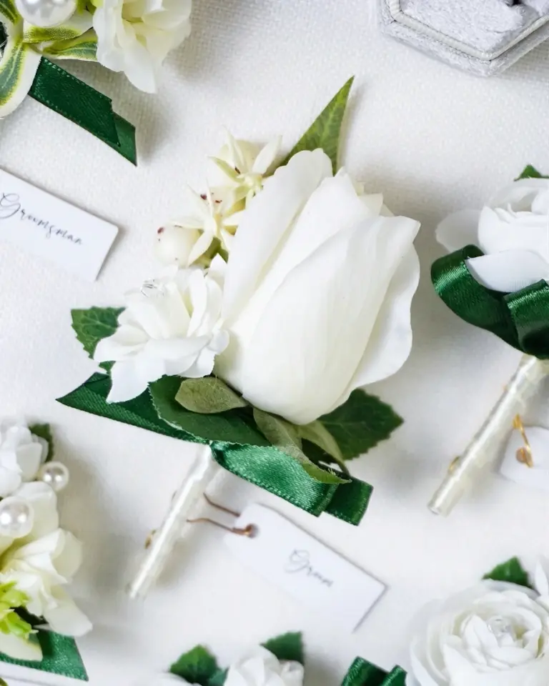 Close-up of the groom's white flower boutonniere from a groomsmen boutonniere set.