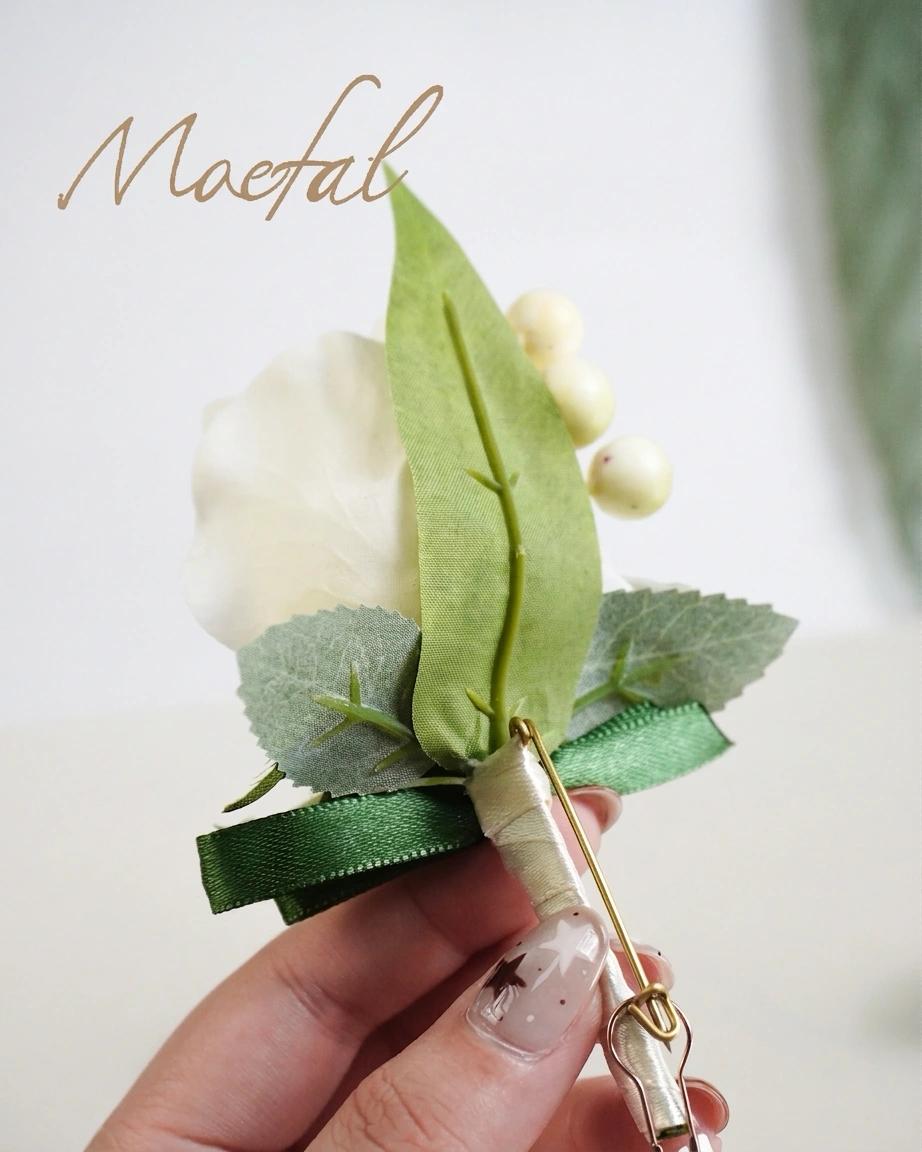 Hand holding the back of a boutonniere showing the built-in safety pin attachment.