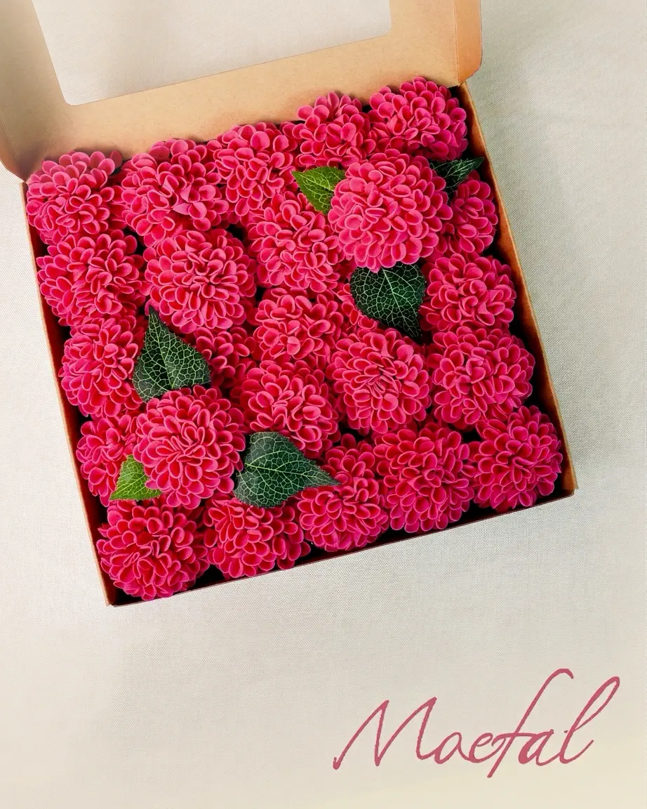 Top-down view of many hot pink artificial dahlia flower heads packed in a box.