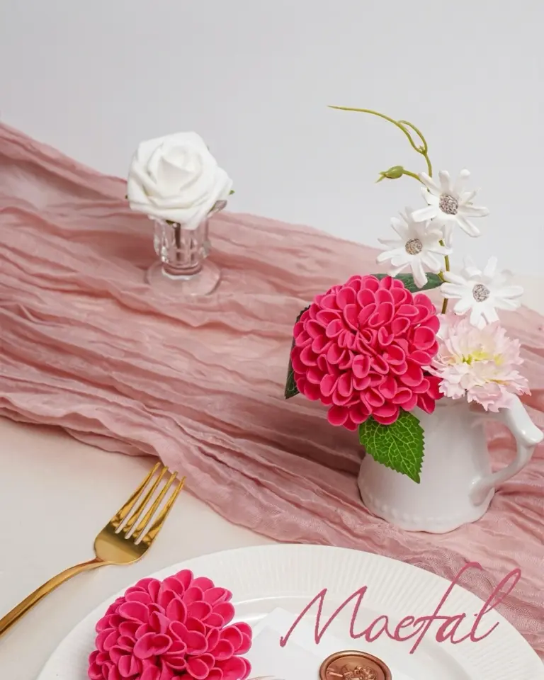 A hot pink artificial dahlia on a plate as part of a wedding table setting.