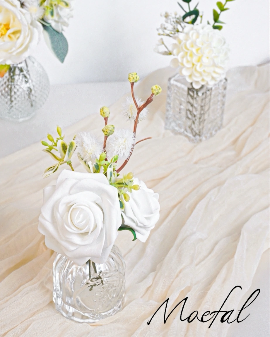 Small glass bud vases with white flowers for an ivory and sage wedding decor.