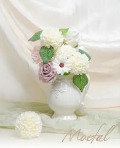 A bouquet of ivory wedding flowers with dahlias and roses in a white pitcher.