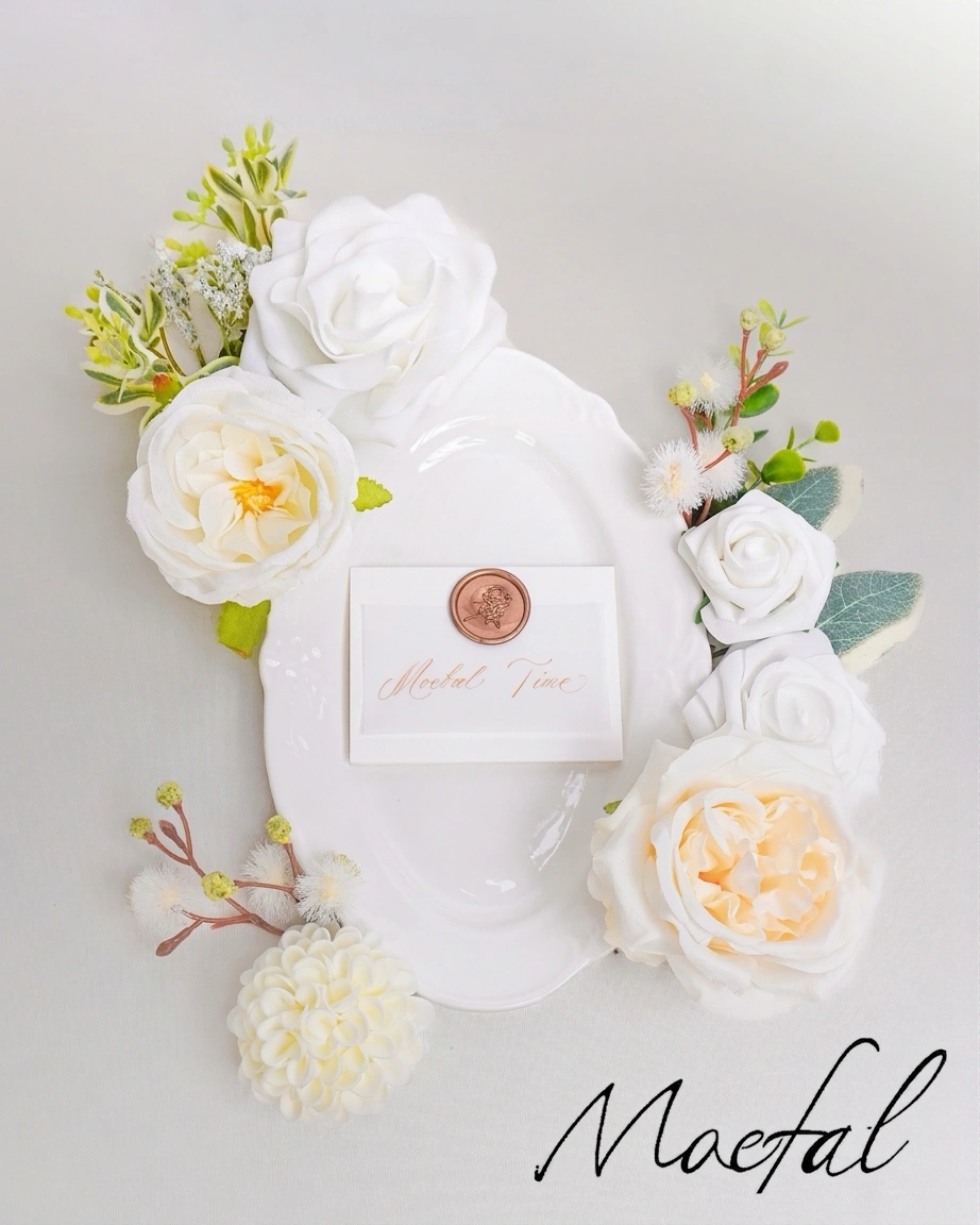 A classic white plate and card surrounded by loose ivory wedding flowers for a tablescape.