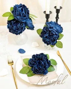 A luxury navy blue wedding table setting with faux peonies on a plate.