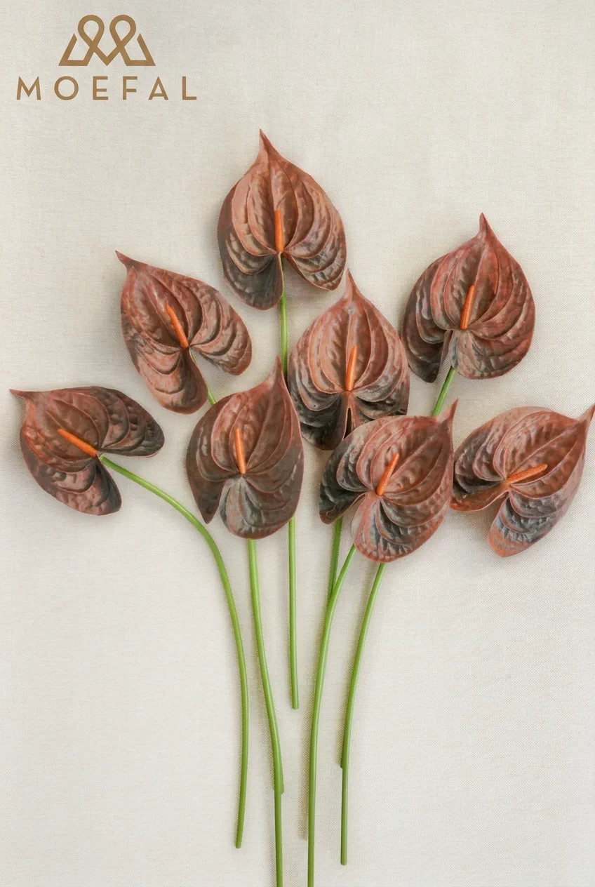A flat lay of several terracotta anthurium stems on a neutral textured linen background.