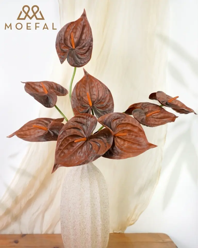 A bouquet of real touch terracotta anthurium flowers in a speckled off-white vase.