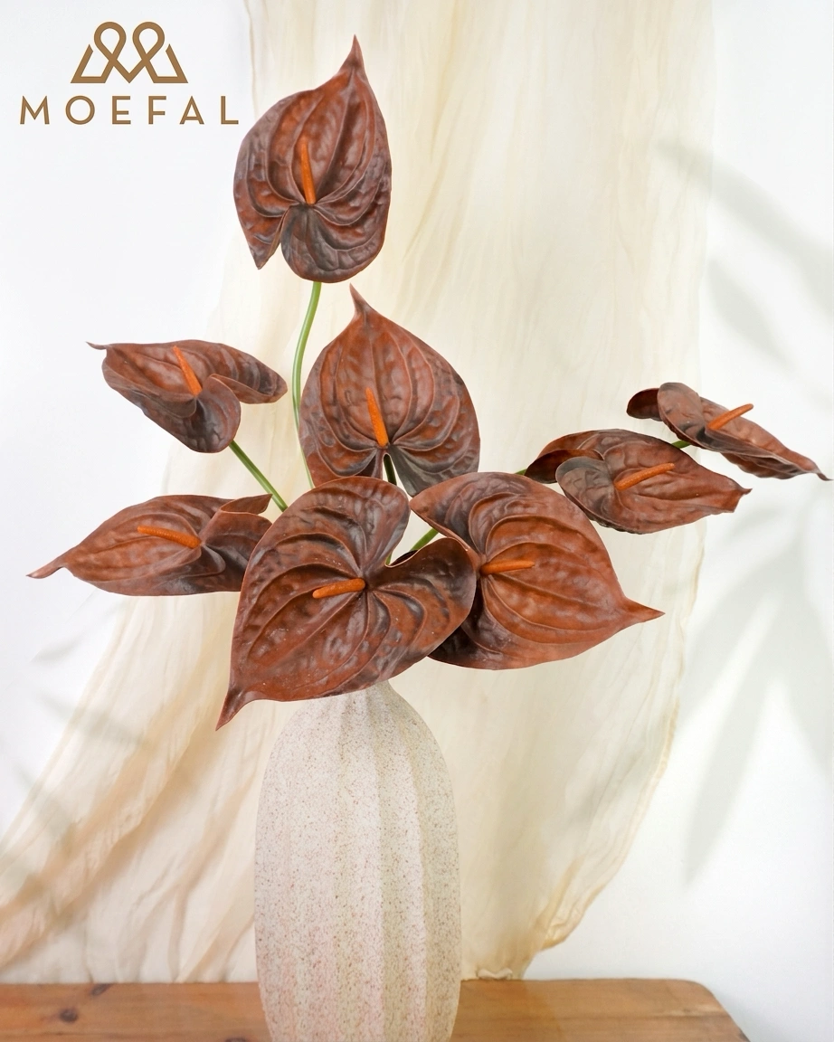 A bouquet of real touch terracotta anthurium flowers in a speckled off-white vase.