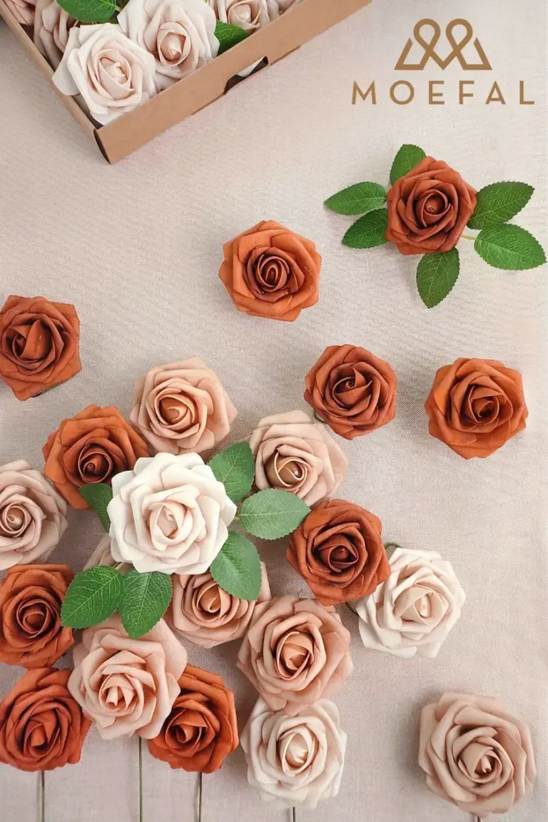 A flat lay of terracotta color palette foam roses scattered on a beige fabric.
