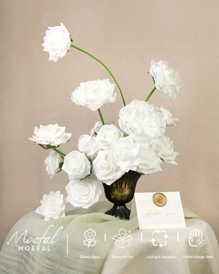 A lush faux arrangement of white peonies and roses in a dark vintage vase.