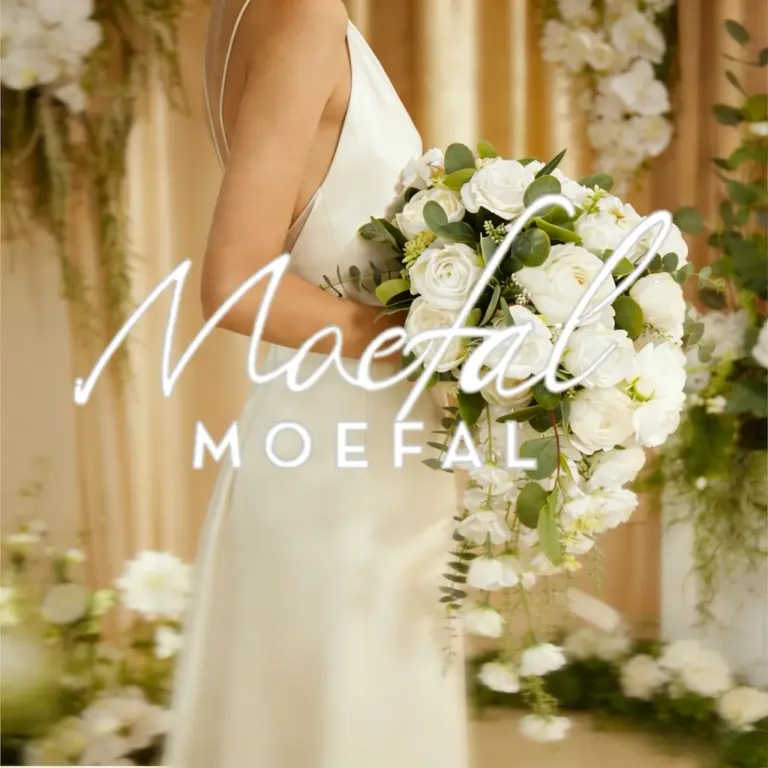 Bride in an ivory slip dress holding a cascading bouquet of white wedding flowers.