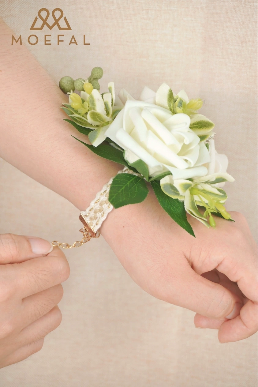 Close-up of hands fastening the adjustable gold clasp of the pearl wrist corsage bracelet.