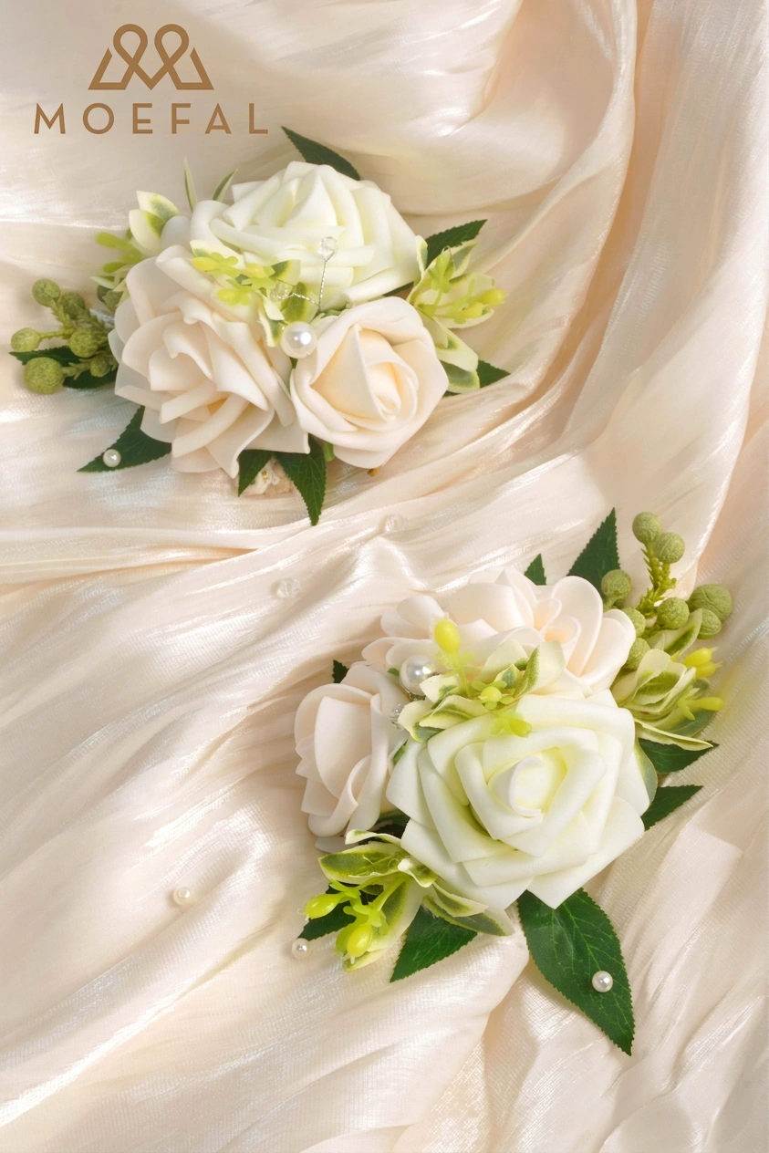 Two ivory rose wrist corsage bracelets displayed on a shimmering cream satin fabric.